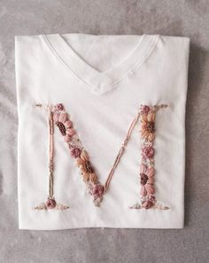 a white t - shirt with the letter m made out of flowers on it's chest