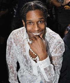 a smiling woman with braids and pearls on her neck posing for the camera in front of a crowd