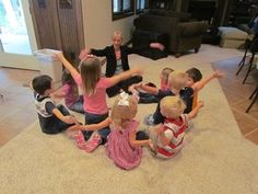 a group of children sitting on the floor playing with wii motes in a living room