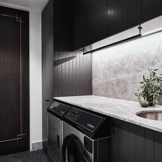 a washer and dryer in a small room with dark wood paneling on the walls