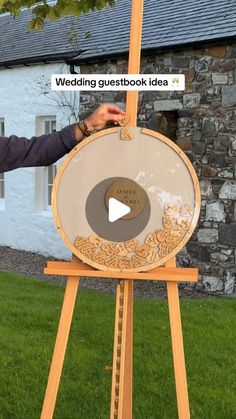 a man standing next to a wooden easel holding an art piece on top of it