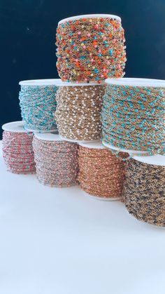 several spools of beaded wire are stacked on top of each other in different colors