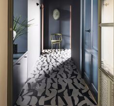 a chair sitting on top of a tiled floor next to a doorway with a potted plant in it