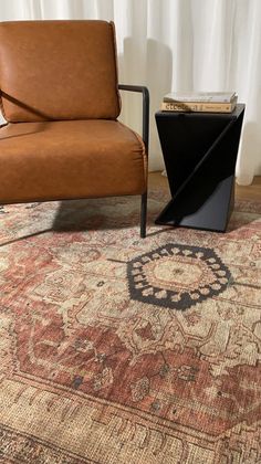 a brown chair sitting next to a black table on top of a rug