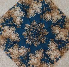 an upside down view of a blue and brown flowered umbrella on the ground with white carpet