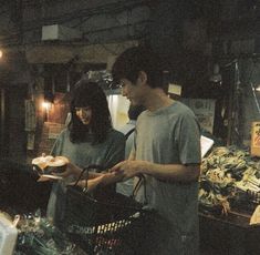 a man and woman standing next to each other in front of a basket filled with food