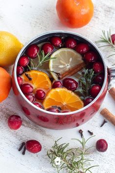 oranges, cranberries and spices are in a pot next to some lemons