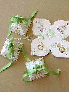 four gift tags with green ribbons tied around them on a brown surface, one has an animal design and the other is a monkey