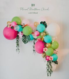 balloons and greenery are arranged in the shape of an arch for a floral balloon arch