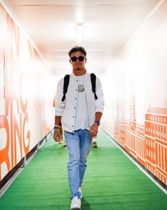 a man walking down a green carpeted hallway