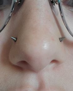 a close up of a person's nose wearing glasses with metal spikes on it