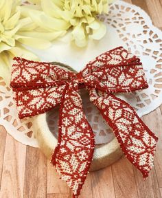 a red and white lace bow sitting on top of a doily next to flowers