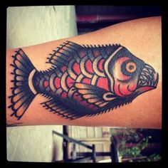 a fish tattoo on the arm with red and black colors in it's body