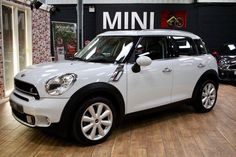 a white mini is parked in a showroom