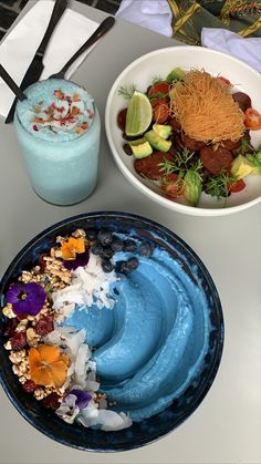 there are two bowls with food on the table next to each other, one is blue