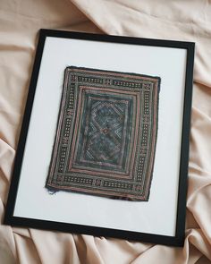 a framed piece of cloth on top of a bed