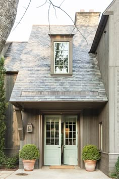 a house with two potted plants in front of it and the door is open