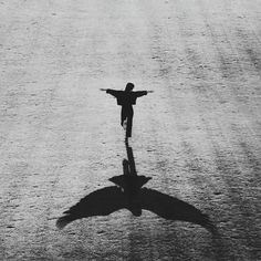 a black and white photo of a person standing in the middle of a field with their arms outstretched