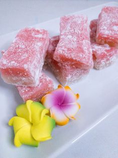 three pieces of pink cake sitting on top of a white plate next to a flower