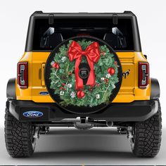 a yellow truck with a wreath and red bow on it's rear tire cover