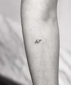 a small saturn tattoo on the left inner arm