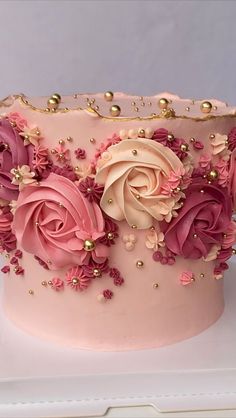 a pink and gold decorated cake with flowers on it