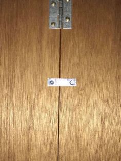 a close up of a wooden door with two metal latches on the front and side