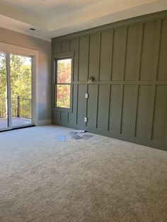 an empty living room with sliding glass doors and large carpeted floor to ceiling windows