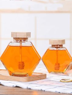 two honey jars sitting on top of a wooden cutting board