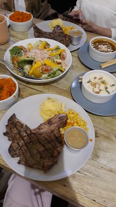 a wooden table topped with white plates filled with food