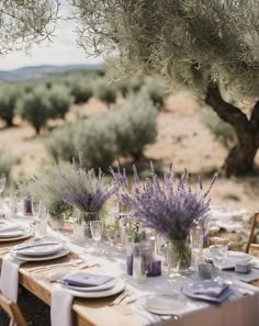 the table is set with lavender flowers and place settings