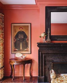 a living room with pink walls and a painting on the wall above a fire place