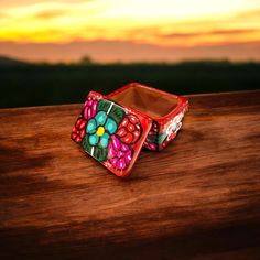 two colorful bracelets sitting on top of a wooden table with sunset in the background