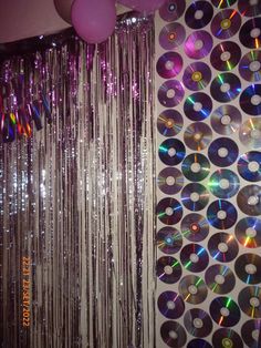 disco balls and streamers hanging from the ceiling in front of a backdrop with cds