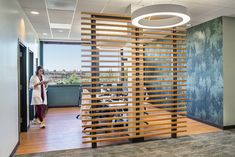 a woman is standing in an office with wood slats on the wall and floor