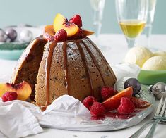 a bundt cake on a plate with fruit and silverware next to it,