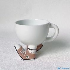 a white coffee cup sitting on top of a pair of shoes