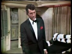 a man in a tuxedo standing next to a bed