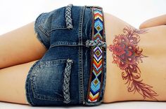 a woman laying on the ground with her stomach covered in tattoos and bracelets,