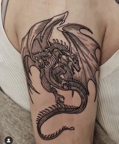 a woman's arm with a dragon tattoo on the back of her shoulder,