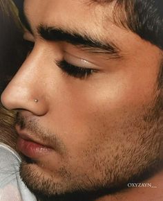 a close up of a man with his eyes closed and nose piercings to the side