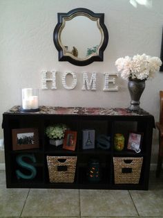 there is a shelf with pictures on it and some flowers in the vase next to it