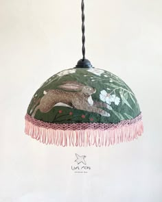 a lamp hanging from a ceiling with an animal design on the fabric and tassels