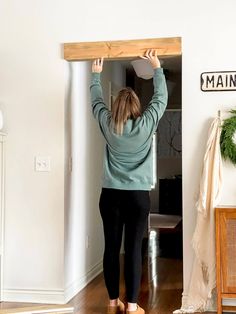 a woman holding up a piece of wood above her head while standing in a living room