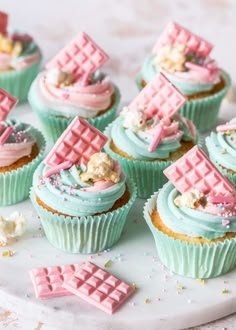 cupcakes with pink and blue frosting are arranged on a white platter