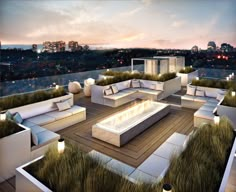 an outdoor living area with couches, tables and fire pit on the roof at night