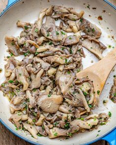 mushrooms are being cooked in a skillet with a wooden spoon