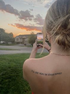 a woman is taking a photo with her cell phone while the sun sets behind her