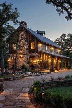 a large stone house with lots of windows and lights in the front yard at night