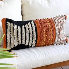 a white couch with two pillows on top of it and a plant in the corner